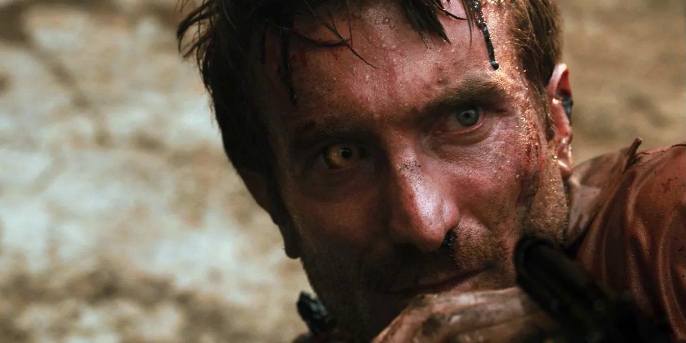 Sharlto Copley as Wikus van de Merwe hiding behind his hand in District 9 Image