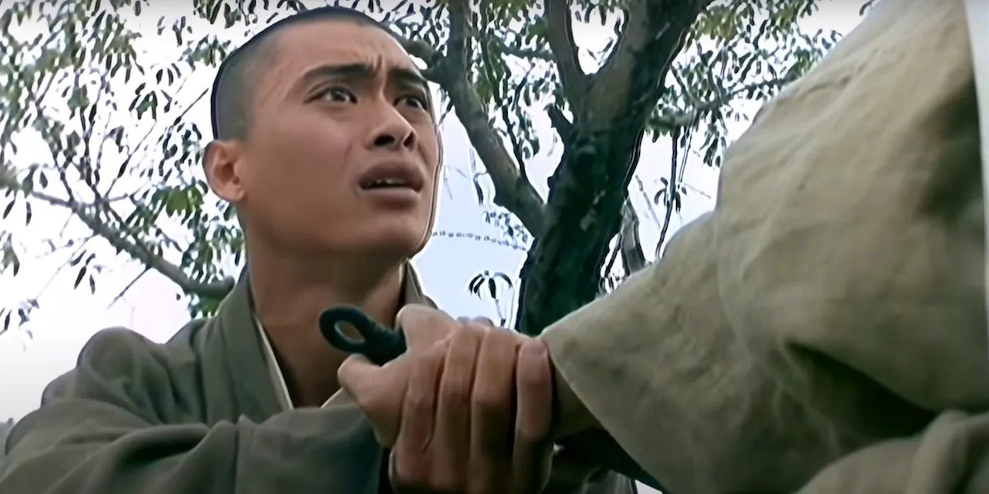 Siu-Wong Fan holds a monk's hand and has a desperate look on his face. Image