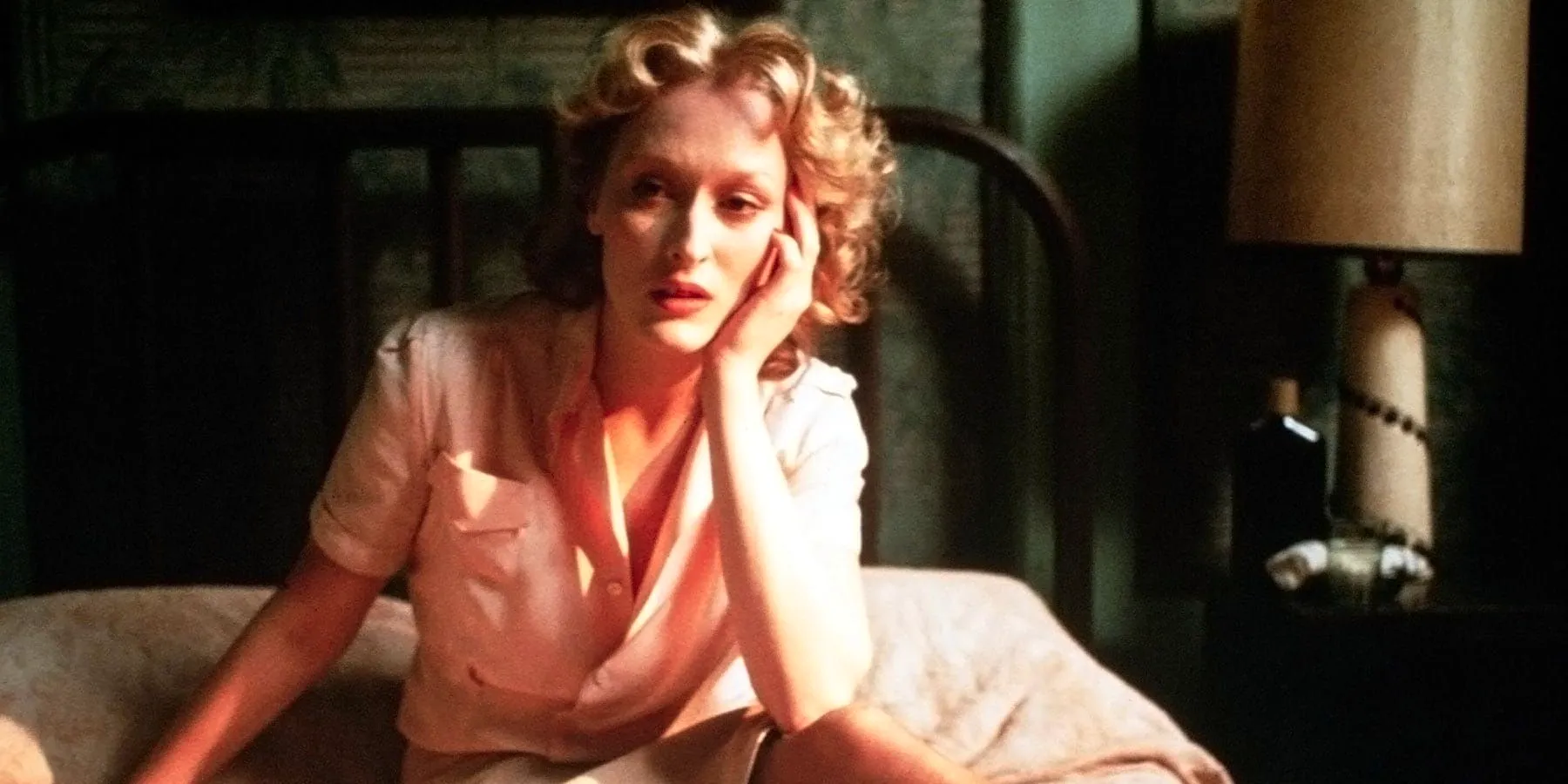 Sophie (Meryl Streep) sitting on a bed with her head resting on her hand in Sophie's Choice. Image