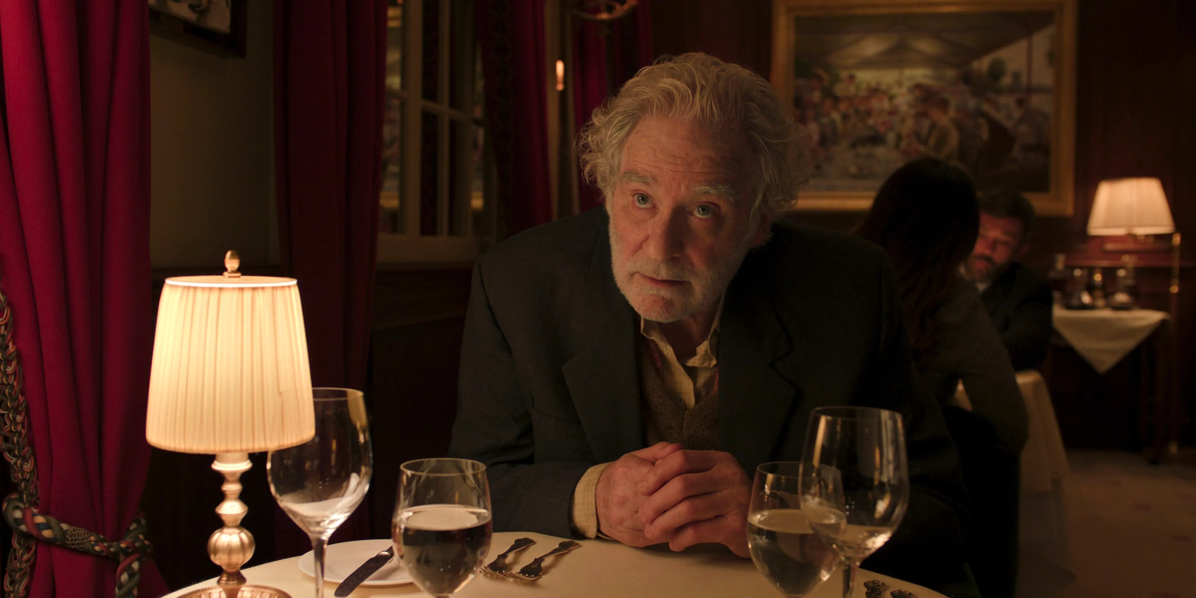 Stephen leaning over a table at a fancy restaurant in Disclaimer Image