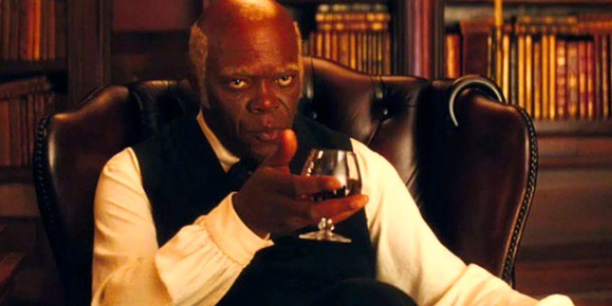 Stephen sitting down and holding a drink in his hand in Django Unchained Image