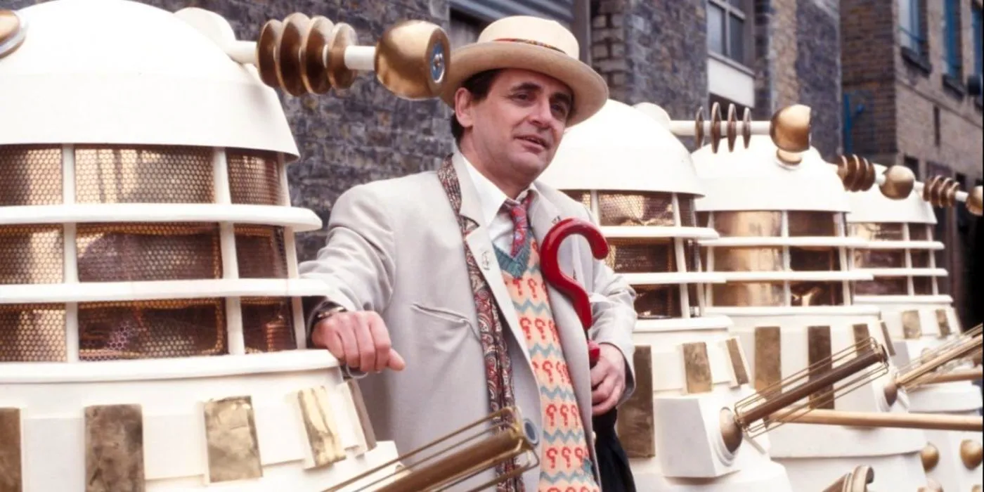 Sylvester McCoy as the Seventh Doctor, posing with several Daleks Image