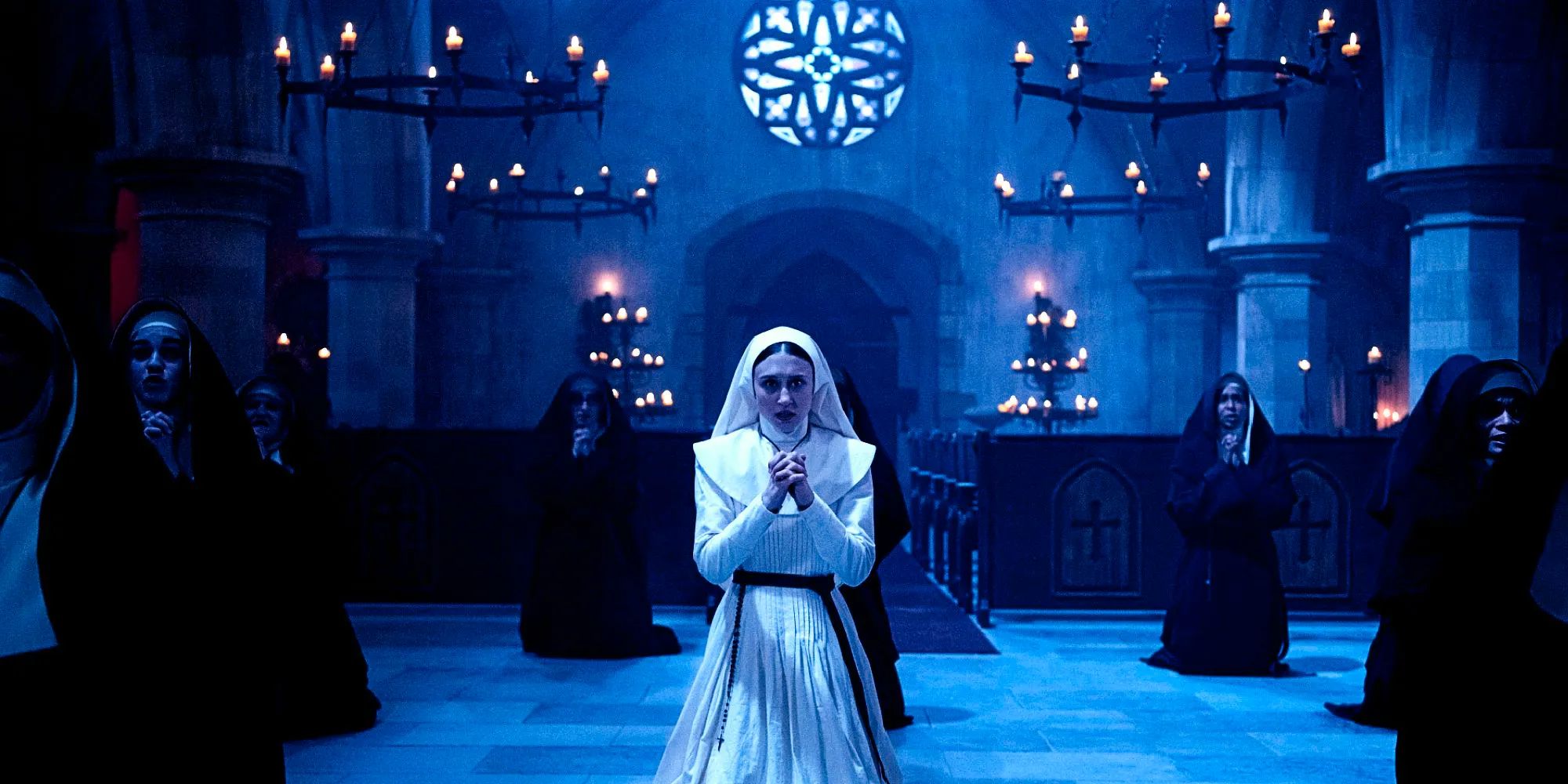 Taissa Farmiga as Sister Irene on her knees praying with other nuns in The Nun Image