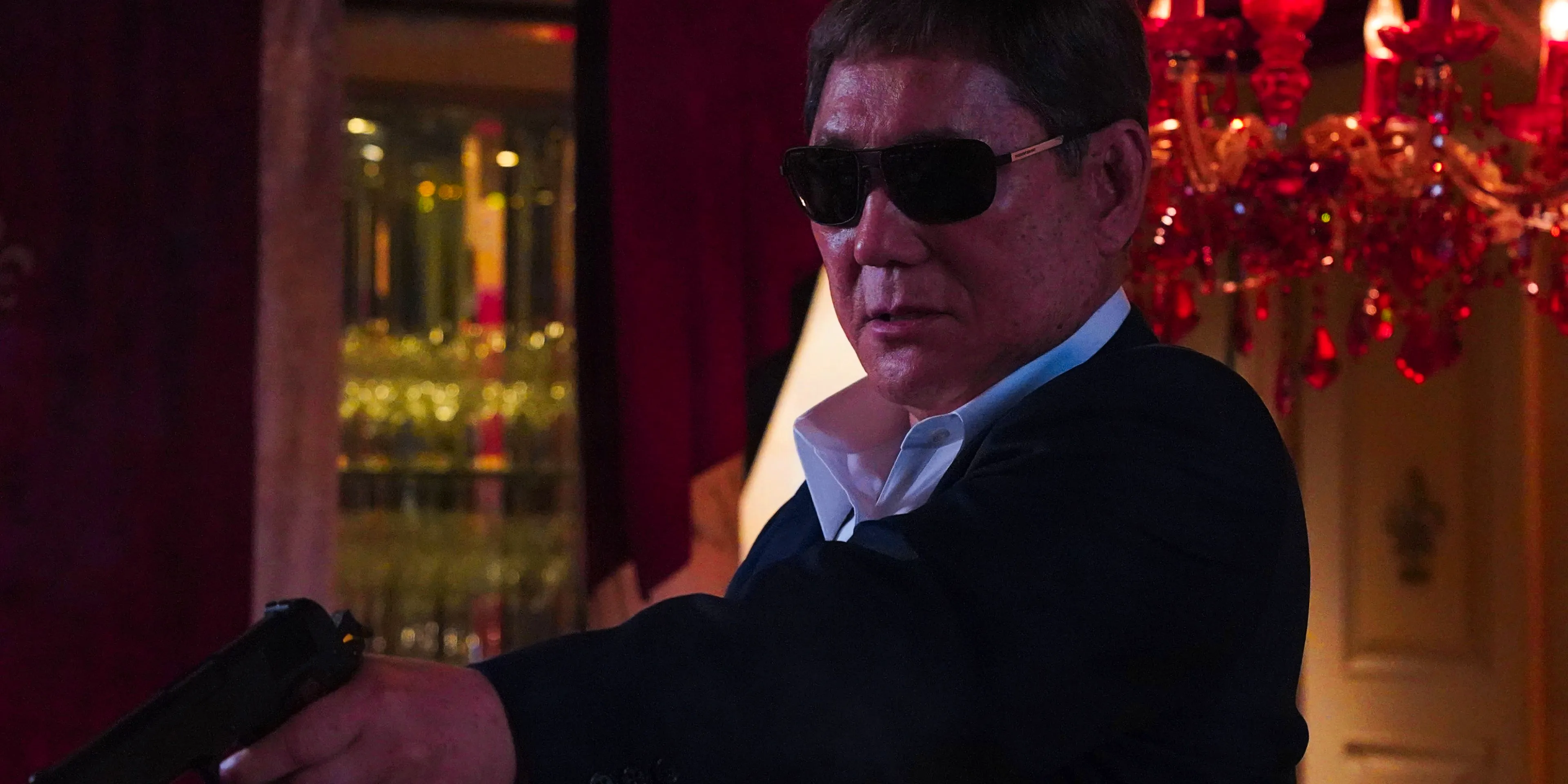 Takeshi Kitano wearing sunglasses and aiming a gun in Broken Rage Image