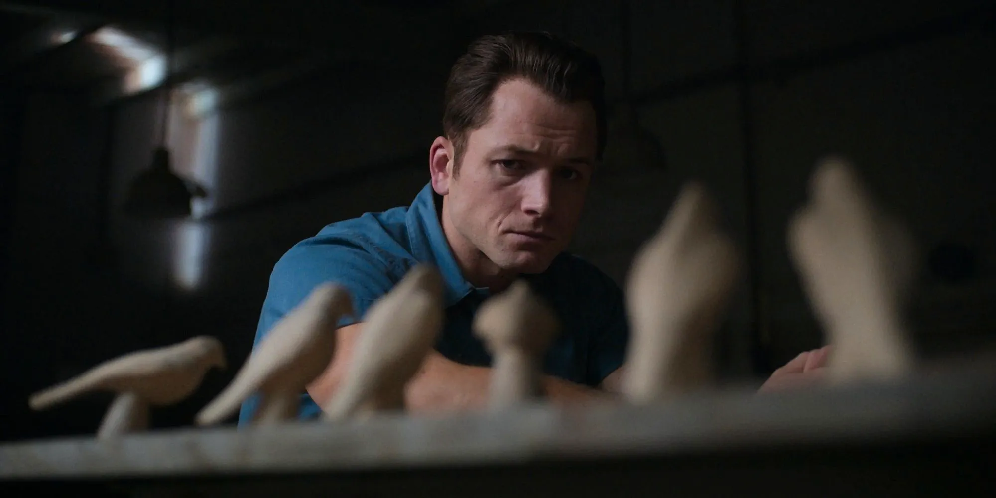 Taron Egerton as James Keene looking at the bird carvings in Black Bird  Image