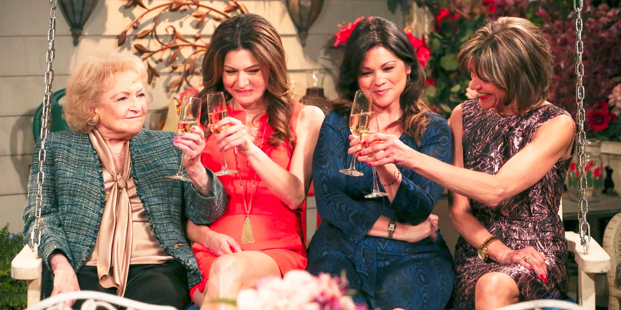 The cast of Hot In Cleveland toasting on a porch swing Image