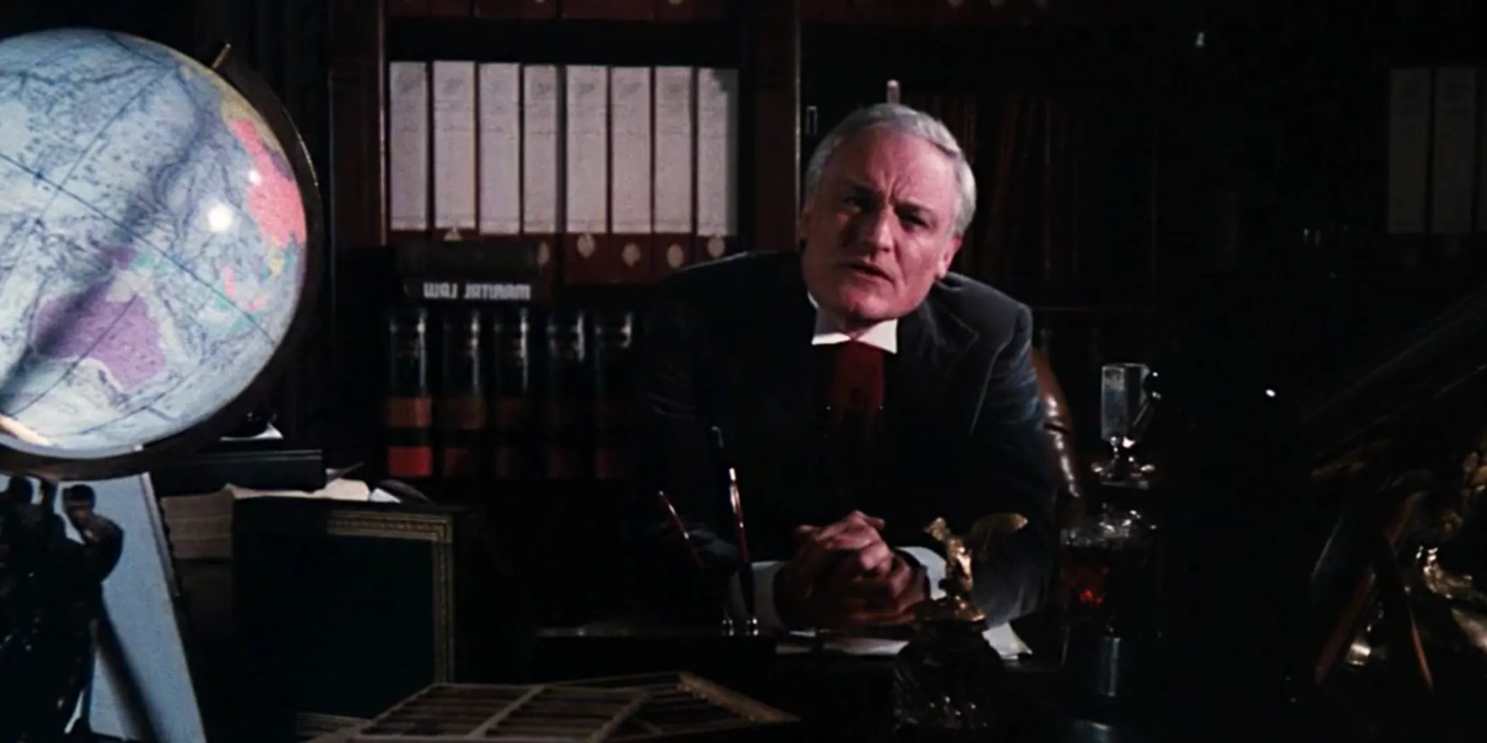 The Criminologist sitting at his desk and talking to the audience in Rocky Horror Picture Show Image