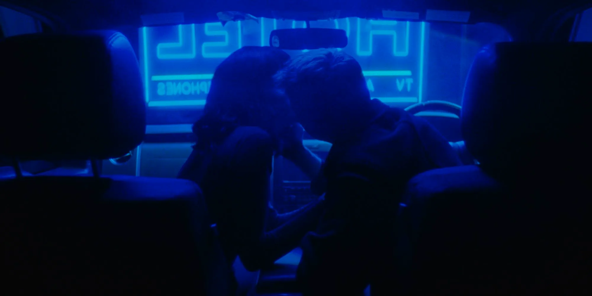 The demon and the lady kiss in blue neon light in Strange Darling Image