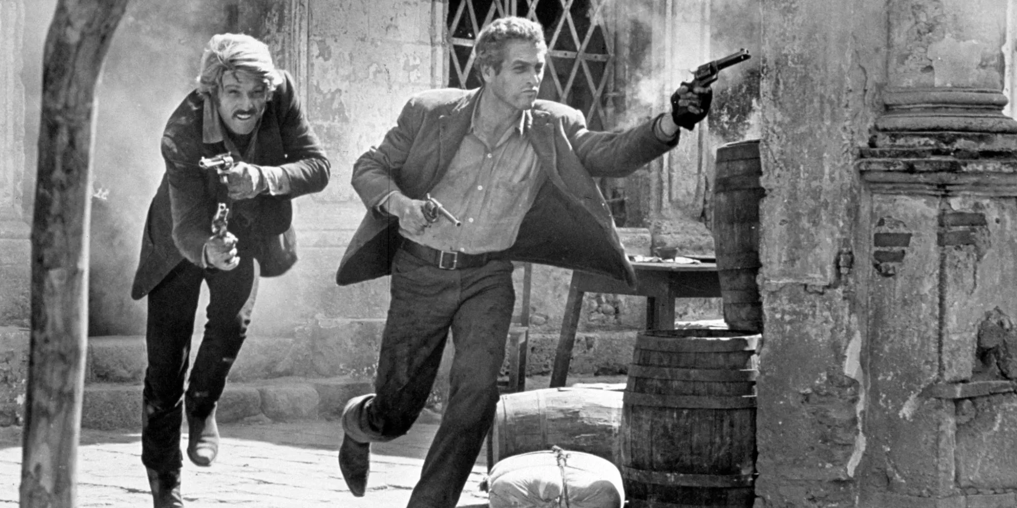 The Ending of Butch Cassidy and the Sundance Kid with Butch Cassidy (Paul Newman) and Sundance Kid (Robert Redford) running and shooting guns in black and white Image