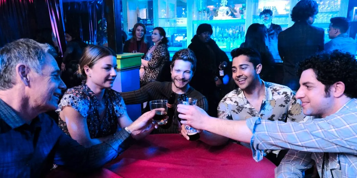 The medical staff of The Resident cheers their drinks at a bar  Image