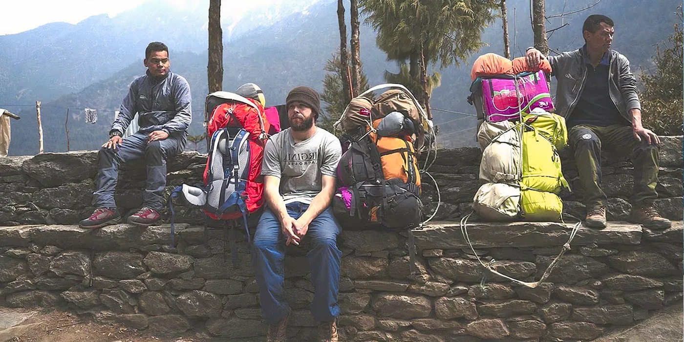 The Porter- The Untold Story at Everest, The Porter is in a grey shirt and its beside a mountain of various climbing bags and equipment alongside two sherpas Image