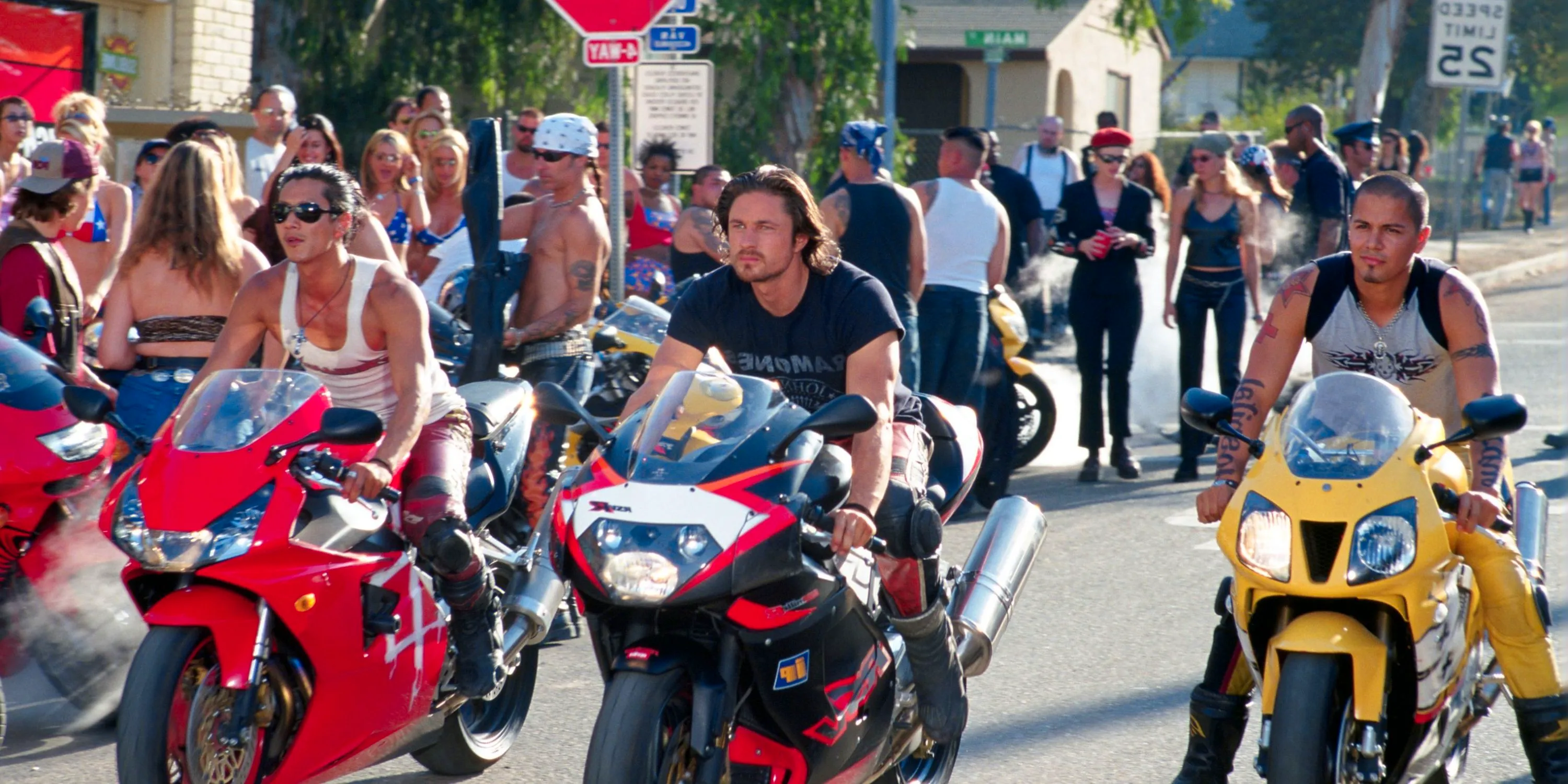 Three bikers in Torque lined up for a street race as a crowd gathers behind them Image