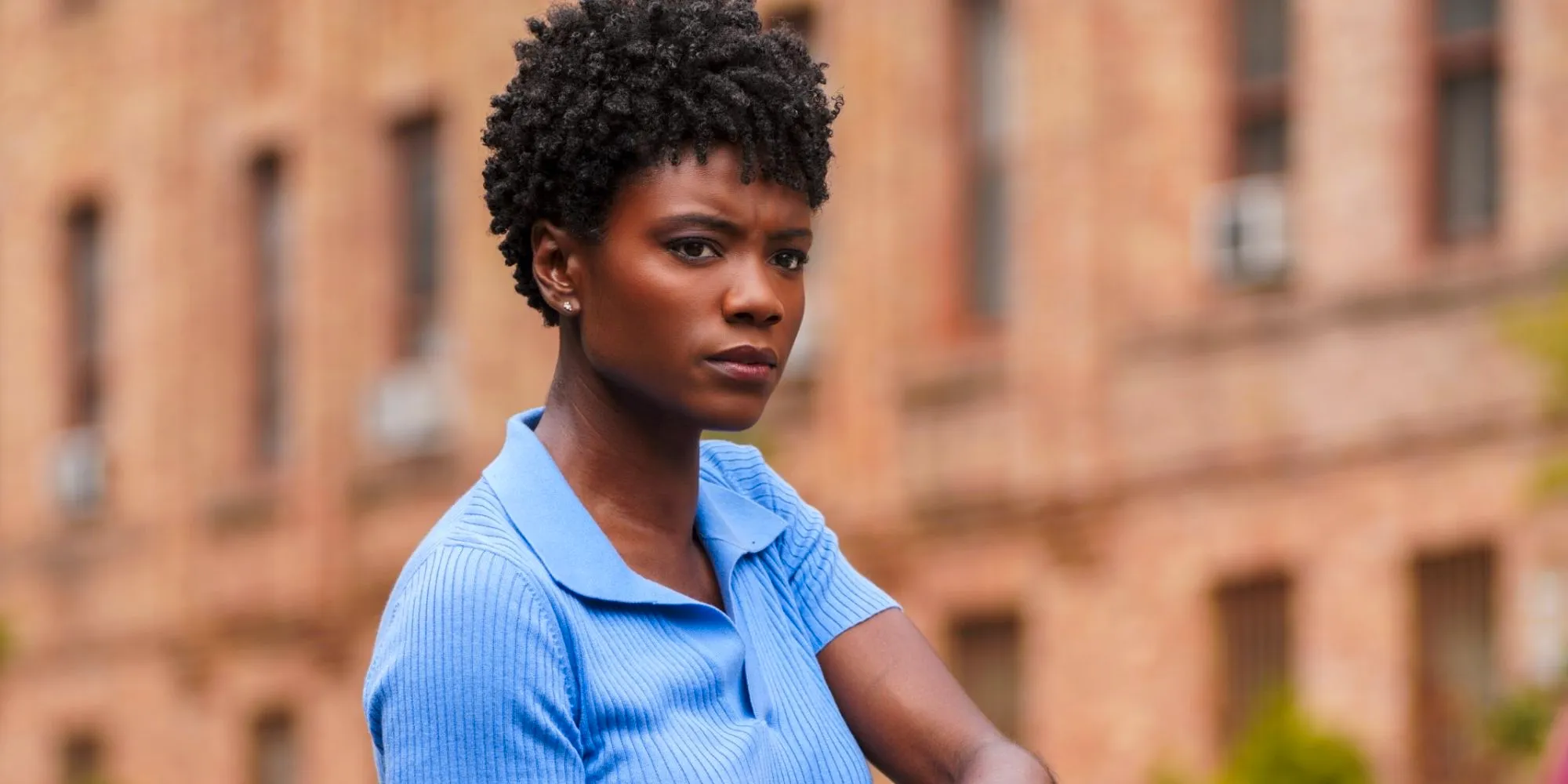 Tiffany Wallace wearing a lilac-collared shirt and standing against the FBI building in FBI Image