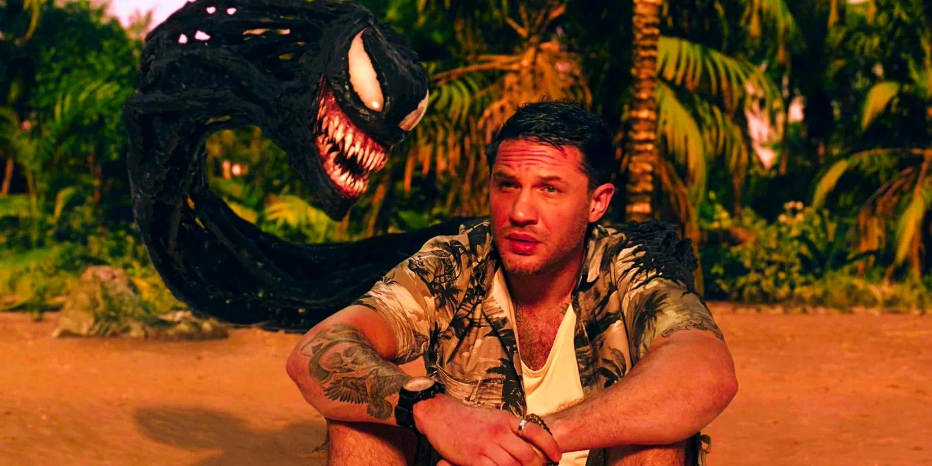 Tom Hardy sat on a beach as Eddie Brock with Venom in Venom Let There Be Carnage Image