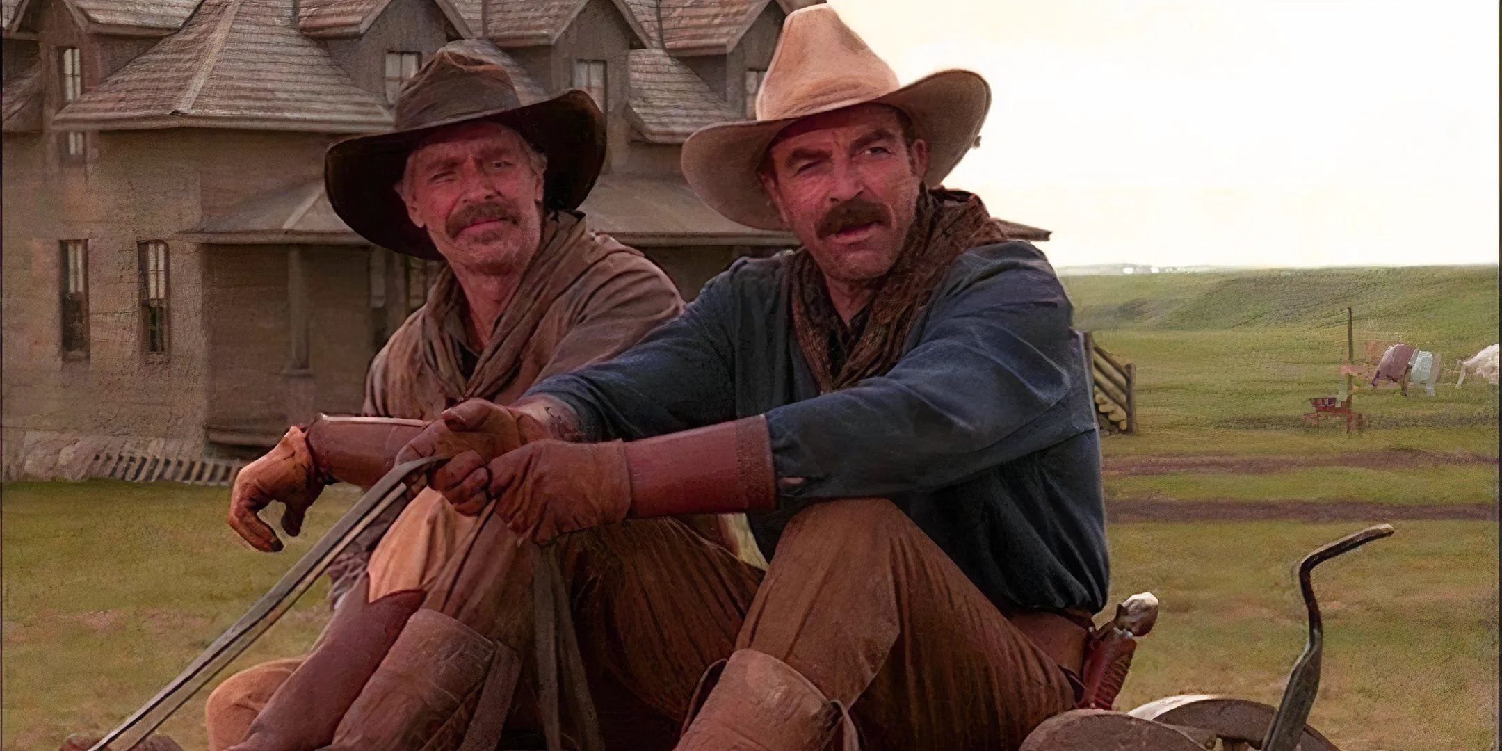 Tom Selleck and Keith Carradine sit next to one another in Monte Walsh.  Image