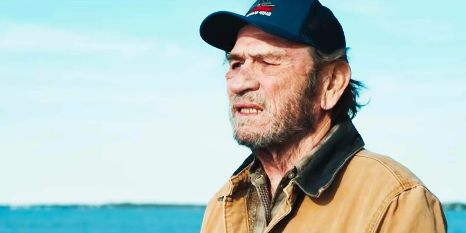 Tommy Lee Jones as Ray Eldridge in a baseball cap staring out somewhere in 2023's Finestkind Image