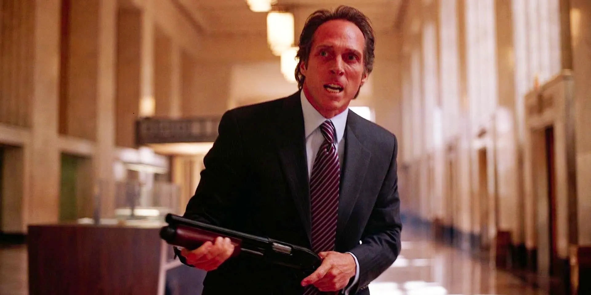 William Fichtner holding a gun while standing in a bank in The Dark Knight Image