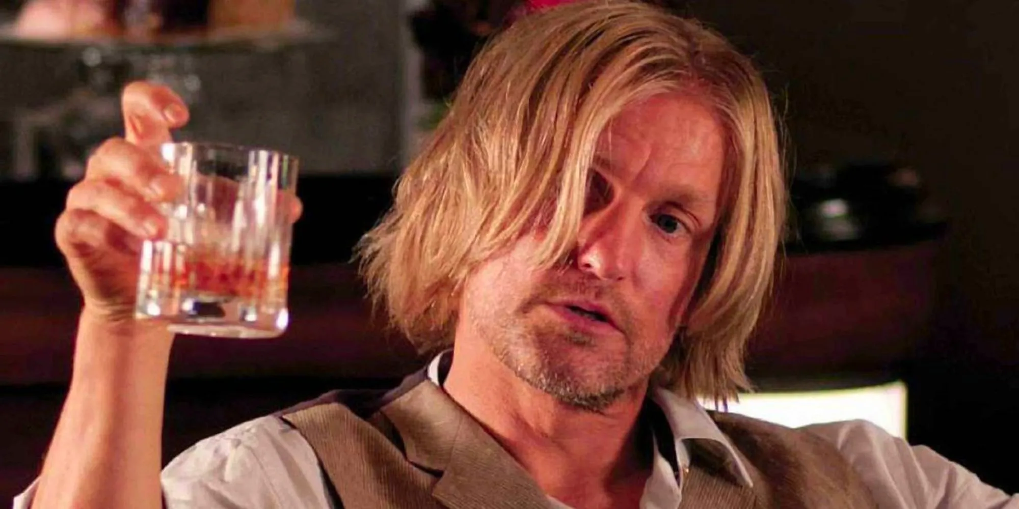 Woody Harrelson as Haymitch holding a glass of alcohol in The Hunger Games Image