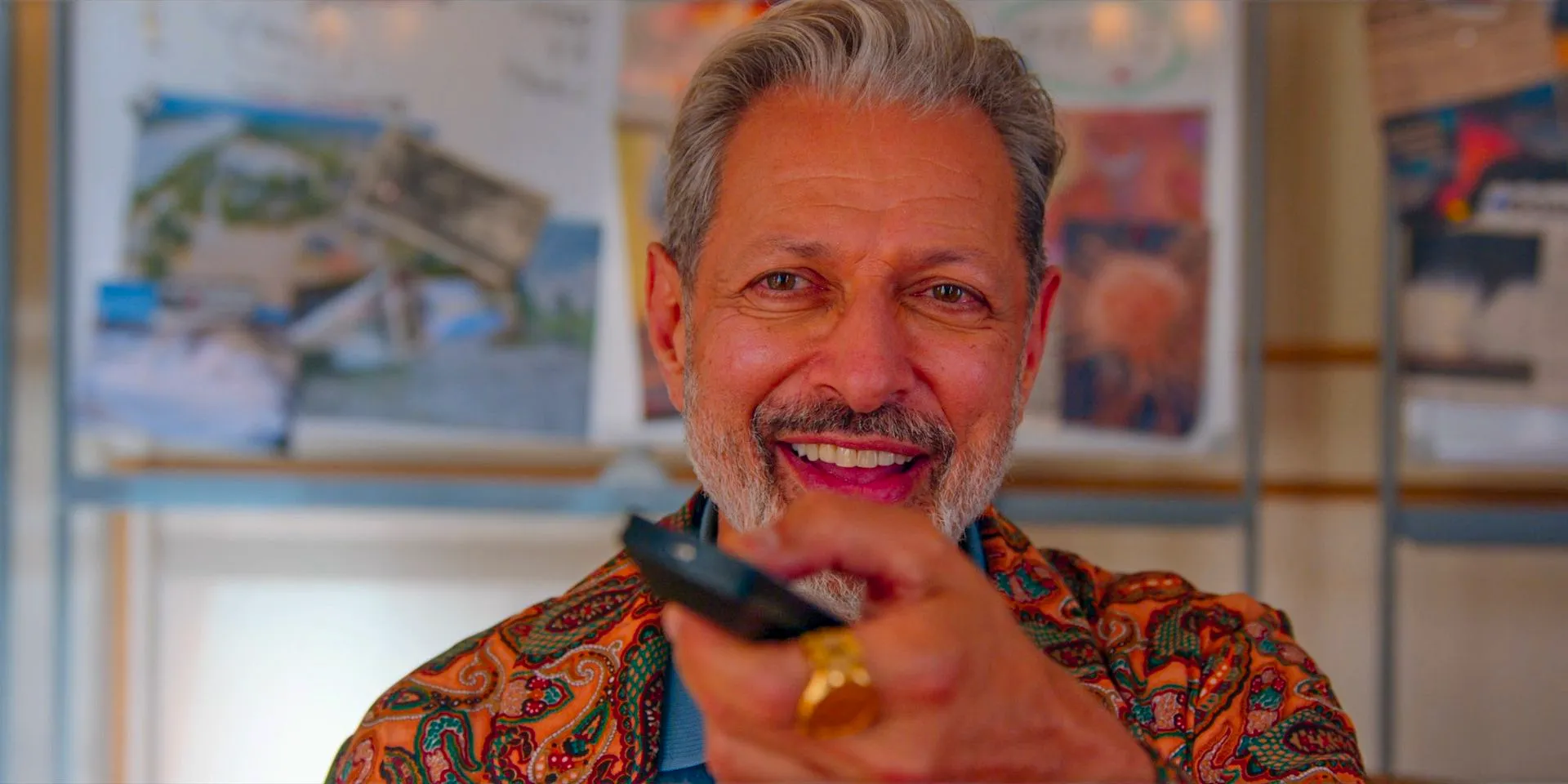 Zeus (Jeff Goldblum) smiling and clicking his TV remote Image