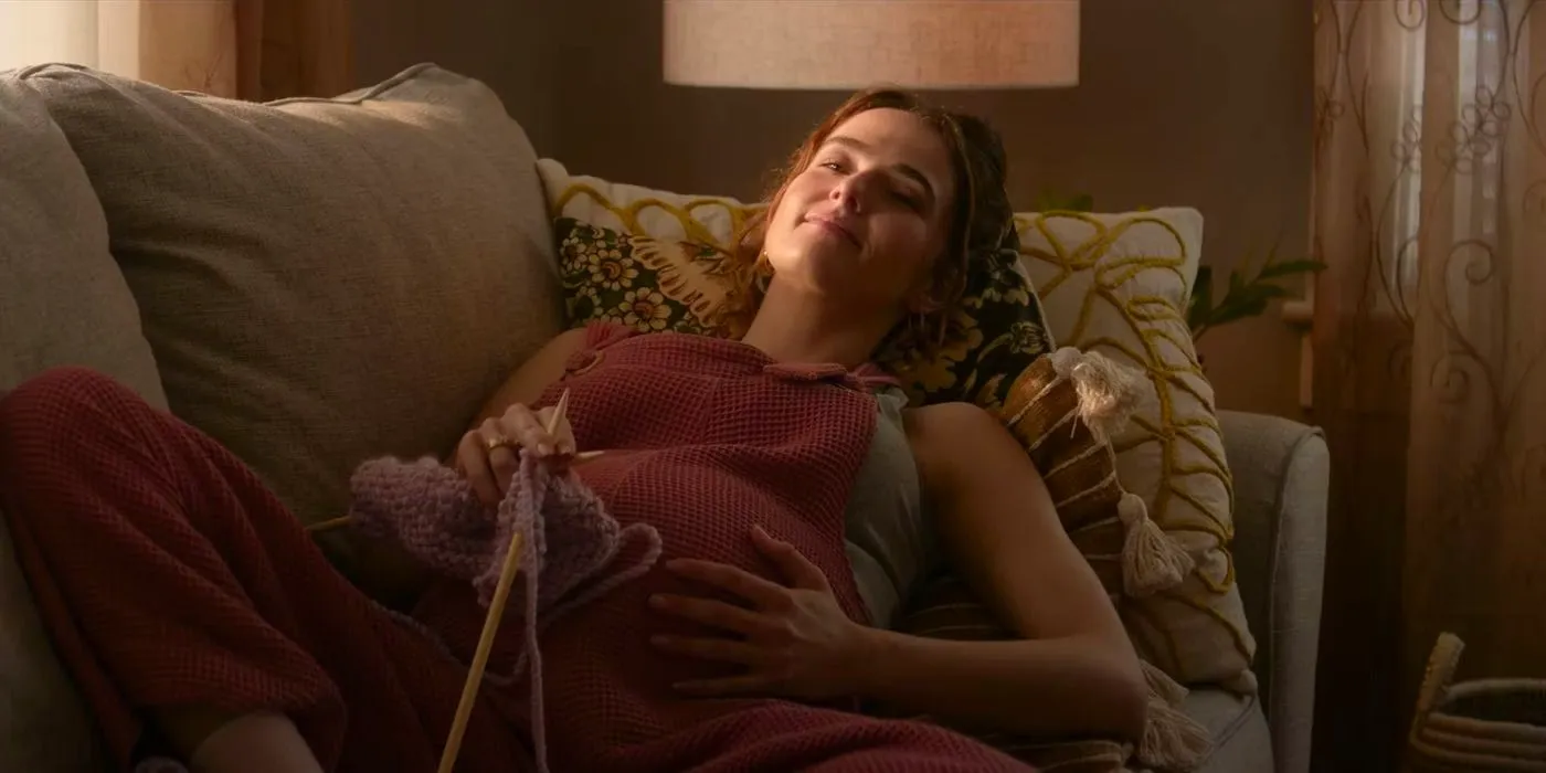 Zoey Deutch pregnant, smiling, and laying on the couch in Juror No. 2 Image